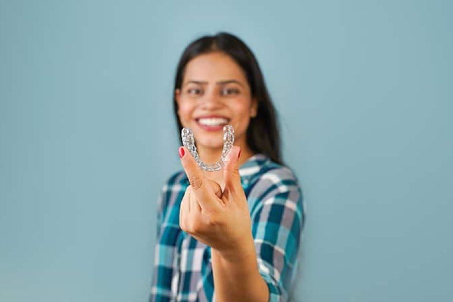 Young Asian Indian woman holding removable invisible aligner, al