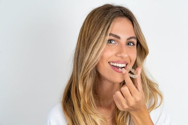 MODEL holding an invisible aligner ready to use it. Dental healthcare and confidence concept.